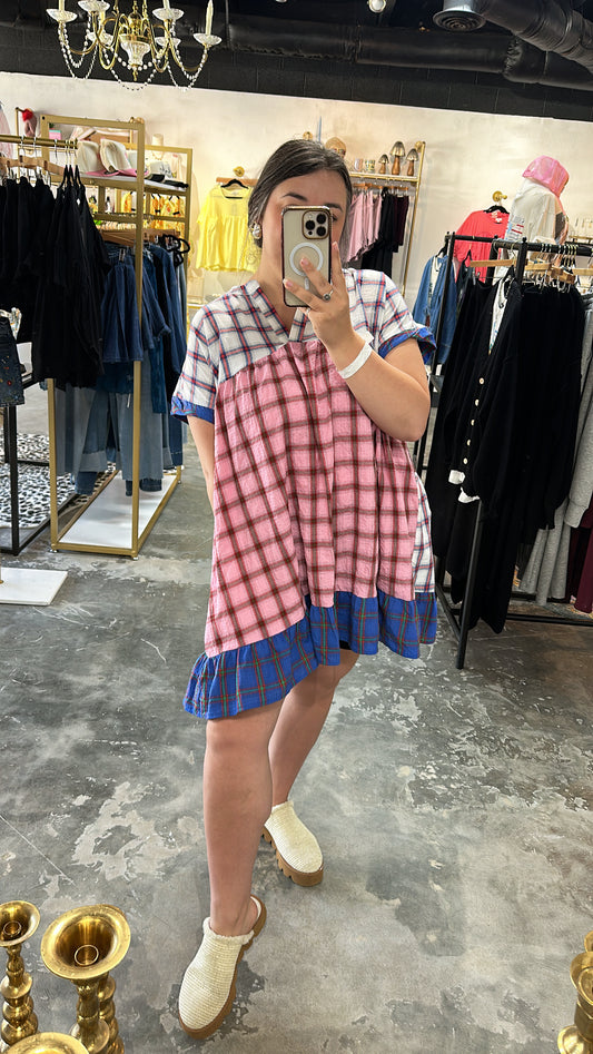 Person wearing a pink and blue checkered dress in a clothing store.
